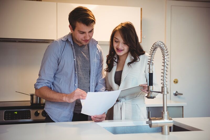 AI Is Changing Home Maintenance Before Something Breaks Couple discussing over digital tablet in kitchen at home