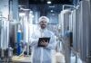 The Importance of Oil Removal in Food Processing Technology Food processing plant interior with positive smiling technologist holding checklist.